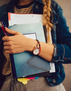 Close-up of hipster woman attending college holding books, notebooks and pens