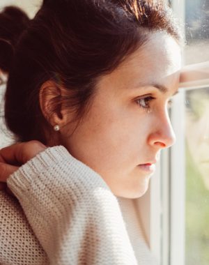 Depressed woman looking through window